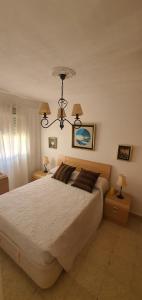 een slaapkamer met een groot bed en een kroonluchter bij Piso luminoso cerca de playa in Cádiz