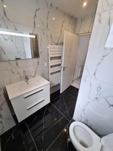 uma casa de banho branca com um lavatório e um WC em La roseraie em Amboise