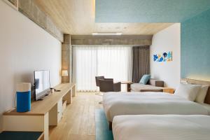 a hotel room with two beds and a television at BEB5 Okinawa Seragaki by Hoshino Resorts in Onna