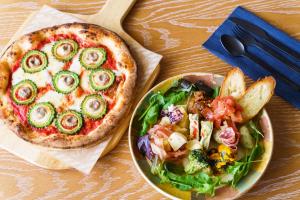 a pizza and a salad on a table with a plate at BEB5 Okinawa Seragaki by Hoshino Resorts in Onna