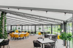 a dining room with tables and chairs and windows at The House in Druskininkai