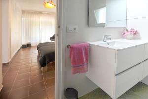 ein weißes Bad mit einem Waschbecken und einem Bett in der Unterkunft ROIG in Sant Martí d’Empúries