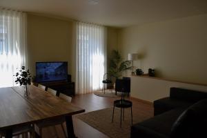 a living room with a wooden table and a television at Glamour Guest House in Viana do Castelo