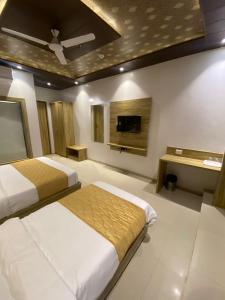 a bedroom with two beds and a flat screen tv at Hotel BKC CROWN - Near Trade Centre, Visa Consulate in Mumbai