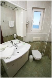 uma casa de banho com um lavatório, um WC e um espelho. em Hotel Viktorija em Seget Vranjica