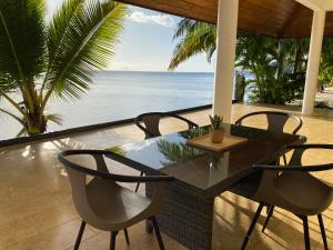 eine Terrasse mit einem Tisch, Stühlen und Meerblick in der Unterkunft Ocean Breeze Villa in Tevaitoa