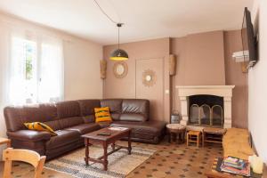 a living room with a brown leather couch and a fireplace at Villa Georges in Foix