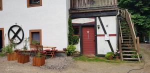 a house with a red door and a table and a ladder at Neumühle in Lutzerath