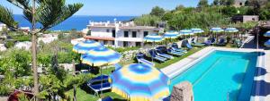 uma piscina com guarda-sóis azuis e brancos e o oceano em Hotel Villa Cimmentorosso em Ischia