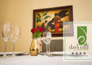 a table with three wine glasses and a vase with a flower at Day's End Guest House in East London