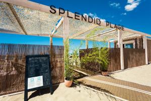 a sign in front of a patio with plants at Hôtel Restaurant Splendid Camargue in Le Grau-du-Roi