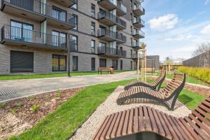 two park benches in front of a building at Downtown Apartments Riverside Nadmotławie - Gym & Free Parking in Gdańsk