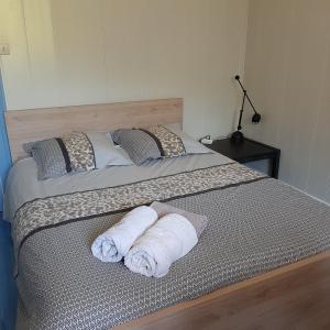 Una cama con dos toallas enrolladas encima. en Beau séjour, en Aiguebelette-le-Lac