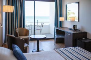 a hotel room with a bed and a desk and a balcony at Hôtel Restaurant Splendid Camargue in Le Grau-du-Roi