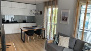 a kitchen and living room with a table and a couch at Apartament Seaside Dune - Aleja Południowa 14A Dźwirzyno in Dźwirzyno