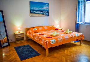 - une chambre avec un lit et une couette en orange dans l'établissement Maslinčica, à Veli Iž
