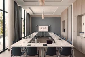 a conference room with long tables and chairs and a screen at OKKO Hotels Paris La Défense in Nanterre