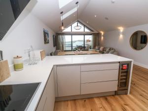a kitchen with white cabinets and a living room at Porth Cove in Newquay