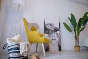 una silla amarilla en una sala de estar con una planta en City Center Accomodation - 101 en Reşiţa