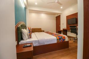 Schlafzimmer mit einem Bett, einem Schreibtisch und einem TV in der Unterkunft FabHotel Lime Tree in Neu-Delhi