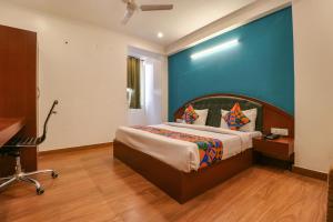 1 dormitorio con cama y pared azul en FabHotel Lime Tree en Nueva Delhi