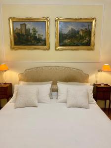 a bedroom with a white bed with two pictures on the wall at Rooftop Garden in Bologna