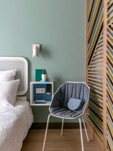 um quarto com uma cadeira ao lado de uma cama em OKKO Hotels Paris La Défense em Nanterre