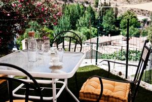 einen Tisch mit Stühlen und eine Flasche auf einer Terrasse in der Unterkunft Las Cuevas de Monachil in Monachil
