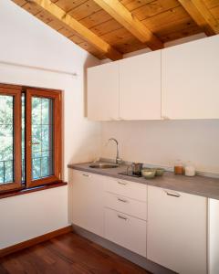 a kitchen with white cabinets and a wooden ceiling at La Casetta, appartamento con vista lago e montagne in San Zeno di Montagna