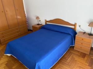 sypialnia z niebieskim łóżkiem i 2 szafkami nocnymi w obiekcie MAR DE BAIONA w mieście Baiona