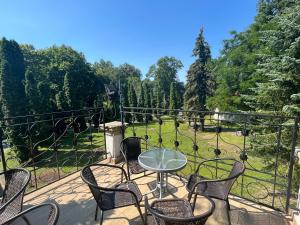 a table and chairs on a balcony with a view of a park at Pałac Victoria in Mgowo