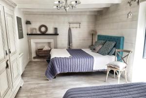 sypialnia z łóżkiem z niebieskim zagłówkiem i kominkiem w obiekcie Le Moulin de Trévelo w mieście Caden