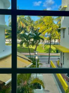 ein Fenster mit Blick auf die Palmen von einem Gebäude in der Unterkunft Beachfront Apt in Carlyle Hotel on Ocean Drive in Miami Beach