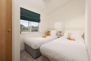 zwei Betten in einem kleinen Zimmer mit Fenster in der Unterkunft Forget Me Not Lodge, 4 Roadford Lake Lodges in Lifton