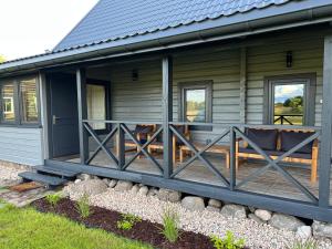 阿尼克什奇艾Rubikių Meldynas Anykščiai的绿色房子,带两个长椅的门廊