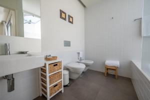 a white bathroom with a toilet and a sink at Pestana Troia Eco-Resort & Residences in Troia