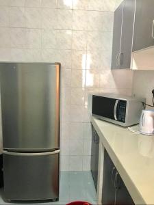La cuisine est équipée d'un réfrigérateur en acier inoxydable et d'un four micro-ondes. dans l'établissement Homestay Tok Wan Puchong Utama, à Puchong
