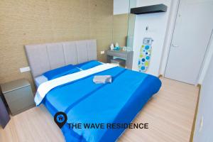 Una cama azul en una habitación con un cartel que lee la residencia de olas en Cardamom The Wave&Atlantis Residence Melaka Town, en Melaka