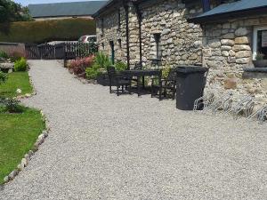a gravel walkway with benches and a stone building at St Mullins Camping in Saint Mullins