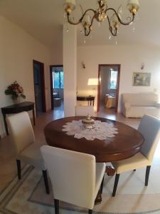 comedor con mesa de madera y sillas blancas en Villa Guido, en Regalbuto