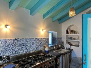 una cucina con piano cottura e piastrelle blu sul muro di IL CORVO DI PIETRA a Scicli