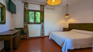 a bedroom with a bed and a desk and windows at Hotel de Montaña La Hortizuela in Coto Rios +31 photos
