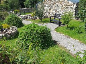 um banco sentado num jardim com uma parede de pedra em St Mullins Camping em Saint Mullins