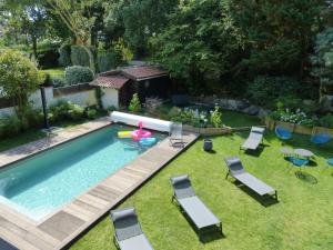 a backyard with a swimming pool with chairs and a pool noodle at CAPBRETON Villa MALBEC Villa rénovée sur jardin pour 10 personnes Wifi gratuit in Capbreton