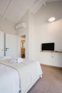 een witte slaapkamer met een bed en een flatscreen-tv bij Locanda Villas in Lefkada +63 foto's