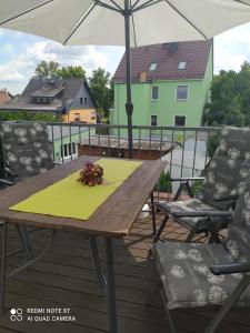 a wooden table on a deck with an umbrella at Domizil der Sinne in Bad Liebenwerda