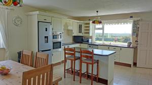 米爾敦馬爾貝的住宿－Southland Holiday Home，厨房配有白色橱柜和桌椅