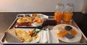 a tray of breakfast foods on a table with orange juice at Blue Lagoon in Baie Lazare Mahé