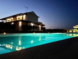 una piscina di fronte a una casa di notte di Country House Andromeda a Offida