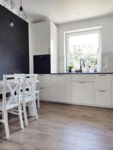 a kitchen with white cabinets and a table and chairs at ablotu - 2-8 person, parking,garden in Świnoujście +13 photos